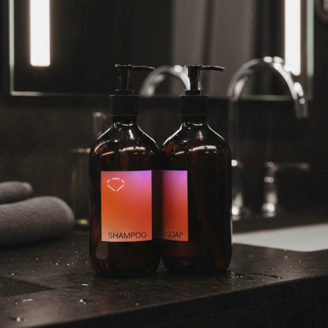 Amber shampoo and soap bottles with gradient Superhero labels in a dark bathroom
