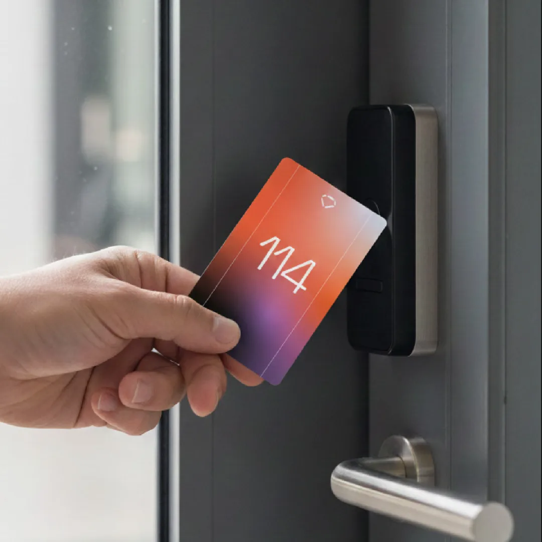 A hand tapping the gradient room key card 114 against a door lock